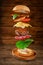 Flying hamburger with ingredients on wooden background. Creative still life concept