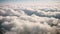 Flying high above, see the white clouds below as the plane descends towards the ground in the distance, flying through white