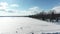Flying high with a drone, going backward, moving away from the Oka village and passing over the ice fishing cabin and the ice