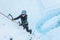 Flying ice as woman swings an ice tool into the glacier ice climbing in Alaska