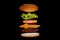Flying ingredients burger or cheeseburger on a small wooden cutting board isolated on a dark background. Burger floating in the