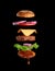 Flying ingredients of a classic cheeseburger sesame bun, onion rings, tomato slices and a juicy barbecue cutlet