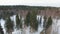 Flying low over snow-covered frozen lake towards winter forest