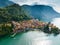 Flying over colorful houses of Varenna village on Lake Como, Italy. Aerial shot of old town Varenna on the coast of Lake