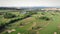 Flying over golf course. Golf fields with green grass and small lake. Aerial view of green hills at countryside landscape. Golf cl