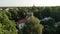 Flying over green forest and looking red rooftop buildings. Estonia flag flying