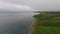 Flying over green rugged cliffs and deserted beach on Sea of Okhotsk coast