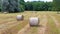 Flying over hay rolls with green, lush forest in background