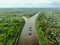 Flying over a large cargo ship with open holds sailing down a calm river surrounded by forest. Carriage of goods by river.