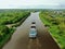 Flying over a large cargo ship with open holds sailing down a calm river surrounded by forest. Carriage of goods by river.