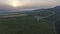 Flying over a large vineyard next to a hill with a sunset panorama