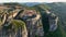 Flying over Meteora Monasteries at sunrise, Greece. Landscape scenery with green hills, rocks, and old Monasteries on it