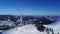 Flying over radio communications tower, mountain snow covered winter landscape.