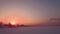 Flying over snow field sunset and lonely chimney-stalk with smoke on the horizon