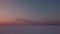 Flying over snow field sunset and lonely chimney-stalk with smoke on the horizon