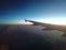 Flying over sunset with plane wing in view. Navy blue sky