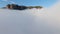 Flying over thick clouds to mountains. Shot. Top view of thick clouds near steep rocky mountains. Beautiful clouds near