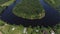 Flying over the wooden houses on the river shore. Shot. Aerial view of a small village and a curved narrow river bending