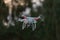 Flying quad copter UAV drone hovering with defocused tree background