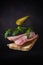 a flying sandwich made from a slice of bread, pork belly, arugula leaves and canned cucumber on a dark gray background with a