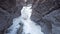 Flying through a snow covered canyon with river below: pristine winter landscape and snow. Flies over rocks and around