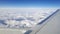 Flying and traveling abroad, view from airplane window on the wing on cloudy blue sky aboard morning winter time, journey