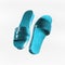 Flying turquoise pair of flat sandals shoes at white background. Fashionable summer footwear with fancy slippers levitating in the