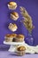 flying Vanilla Caramel Nuts Muffins In Paper Cups with reeds vase on purple background