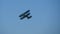 Flying of vintage two propeller biplane in air. Double winged propeller airplane passing in the clear blue sky during