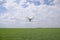 Flying white quadrocopters over a field of wheat