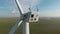 Flying at wind generators. Shot. Beautiful landscape with wind power generators on green fields. Windmills generate