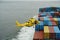 Flying yellow helicopter with Columbia River Bar pilot over containers.