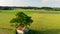 Flyover aerial view of rural landscape with barn under a large tree