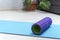 Foam roller for self-massage on blue yoga mat. Equipment for myofascial release. Massage roller. MFR