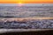 Foam sea wave rushes onto seashore at sunset