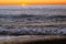 Foam sea wave rushes onto seashore at sunset
