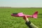 A foam throwing plane-glider in the hand of a woman on the background of a green field