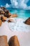 Foam wave between rocks on Grand Anse beach, La Digue, Seychelles. White clouds, crystal clear ocean and lonely luxury