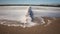 Foamed water on the breakwater and a pier in the sandy beach