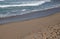 FOAMY BACKWASH ON BEACH DISPLAYING WET SAND