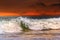 Foamy sea wave against the backdrop of a dramatic red sunset