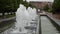 Foamy streams of water rise and fall. Alley of fountains in a city park