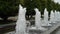 Foamy streams of water rise and fall. Alley of fountains in a city park