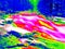 Foamy water level of waterfall, curves between boulders of rapids. Water of mountain river in infrared photo. Amazing thermography