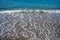 Foamy wave reaching the calm beach. Front view