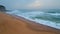 Foamy waves covering sandy coast at gloomy day closeup. Ocean surf rolling beach