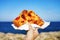 Focaccia barese slice with Mediterranean sea on background. Focaccia pugliese against blue sea and sky. Bari-style focaccia bread