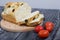 Focaccia bread with olives and sun-dried tomatoes. Several red tomatoes are nearby. On pine boards