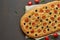 Focaccia, pizza, italian flat bread with tomatoes, olives and rosemary on brown table, copy space