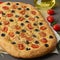 Focaccia, pizza, italian flat bread with tomatoes, olives and rosemary on brown table, side view